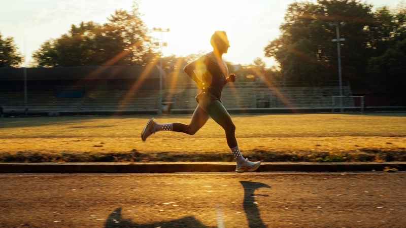 Coureur en pleine foulée sur une piste au coucher du soleil