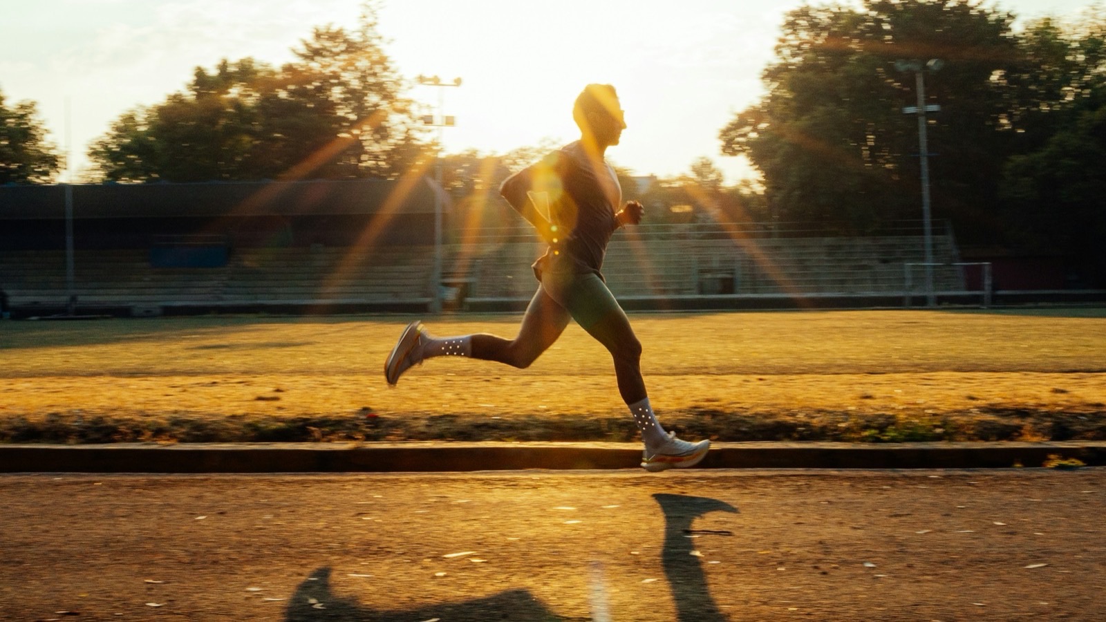 Coureur en pleine foulée sur une piste au coucher du soleil